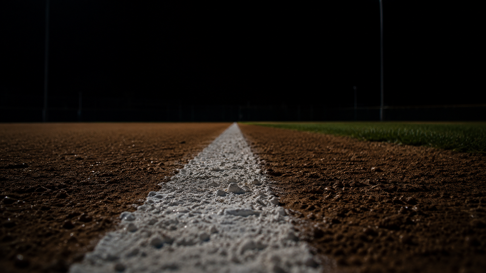 Chalk foul line on a baseball field at night